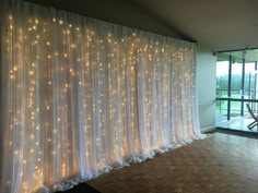 a room with white curtains and lights on the wall