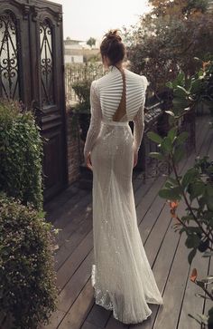 a woman in a long white dress walking down a wooden walkway