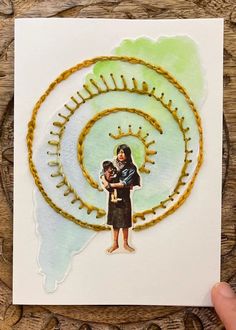 a person holding a child in front of a spiral design on a piece of paper