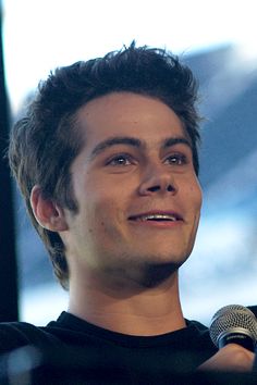 a young man holding a microphone in front of his face and looking off to the side