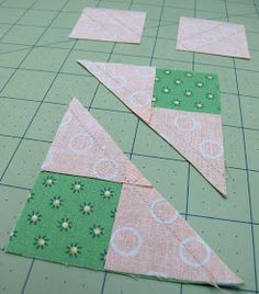 some green and pink pieces of fabric sitting on top of a cutting mat with scissors