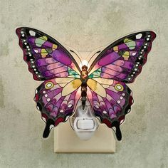 a purple butterfly sitting on top of a light switch