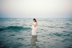 a pregnant woman standing in the ocean water