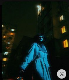 a man standing in front of a tall building at night