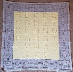 a crocheted blanket with the letters and numbers on it, sitting on a carpet