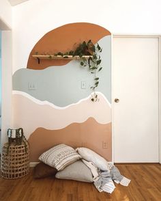 a room with wood flooring and painted mountains on the wall, along with pillows