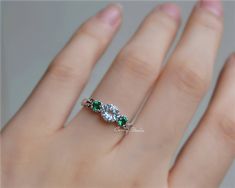 a woman's hand with a diamond and emerald ring