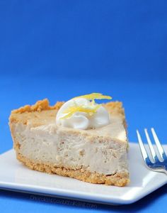 a piece of cheesecake on a white plate with a fork next to it and a blue background