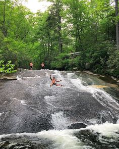 a man falling off his surfboard into the water in a river surrounded by trees