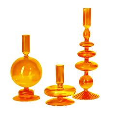 an assortment of yellow glass objects on a white background, including one vase and two candlesticks