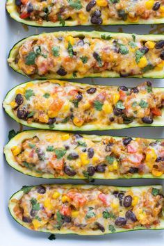 four stuffed zucchini boats filled with black beans, cheese and cilantro