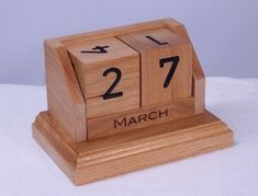 a wooden block clock with the date march 27 on it's face and numbers marked in black