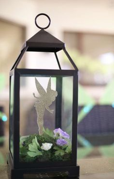 a glass lantern with a fairy on it and flowers in the bottom right hand corner