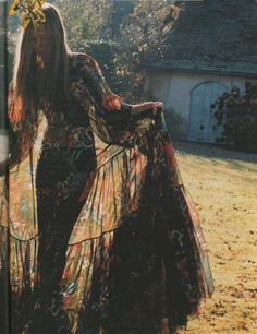 a woman standing in the grass wearing a long dress