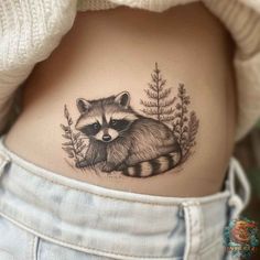 a small raccoon tattoo on the stomach