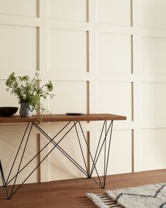 a wooden table sitting on top of a hard wood floor next to a white wall