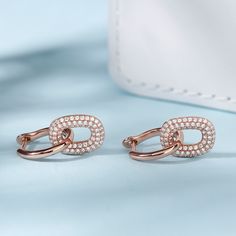 A striking twist on traditional hoop earrings, these beautifully designed dangles will add graceful movement and chic, contemporary style to any look. Highlighted by two interlocking, geometric hoops, designed in high polished sterling silver and glittering stones. For eye-catching movement and a dash of cool, contemporary style choose these chic dangle earrings.Carat Weight: 1.44 ctStone Size: 1 mmStone Type: Jeulia® StoneNumber of Stones: 144 Stone Shape: RoundStone Color: Diamond WhiteWeight: Modern Small Hoop Rose Gold Earrings, Modern Rose Gold Small Hoop Earrings, Modern Rose Gold Dangle Earrings, Modern Clip-on Dangle Hoop Earrings, Modern Rose Gold Drop Earrings, Modern Twist Matching Drop Earrings, Modern Twist Jewelry With Matching Dangle Earrings, Modern Twist Dangle Jewelry With Matching Earrings, Interlocking Design