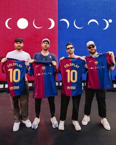 three men holding up jerseys in front of a red and blue wall