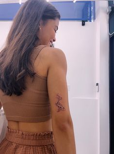 a woman with a small tattoo on her left arm is looking down at the floor