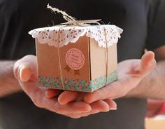 a person holding a small gift box in their hands with lace on the top and bottom