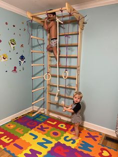 two children climbing on a ladder in a play room with colorful rugs and wall decals