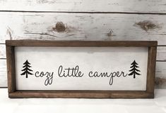 a wooden sign that says cozy little camper with pine trees on the bottom and black lettering