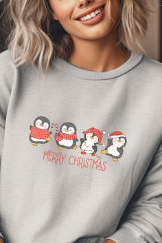 a woman wearing a merry christmas sweatshirt with penguins on the front and bottom, smiling at the camera