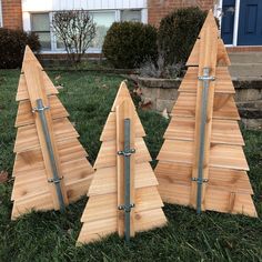 three wooden christmas trees sitting in the grass