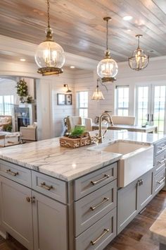 a large kitchen with an island in the middle and two pendant lights hanging from the ceiling