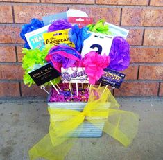 a gift basket filled with lots of colorful items next to a brick wall and yellow ribbon