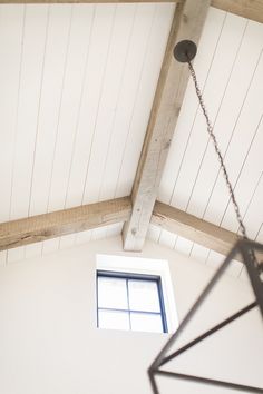 an open window on the side of a white painted wall in a room with wood beams