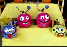 three decorated pumpkins sitting on top of a yellow tablecloth covered table with decorations