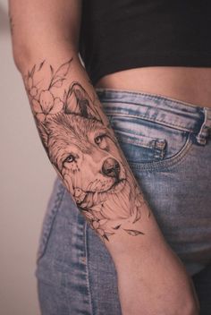 a woman's arm with a tattoo on it that has a wolf and flowers on it