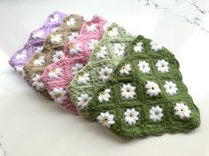 three crocheted dishcloths with white flowers on them sitting on a counter