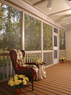 an empty porch with chairs and flowers on the floor next to large sliding glass doors