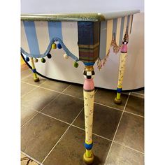 an odd looking table with colorful decorations on it's legs and some balls hanging from the top