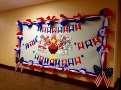 a happy birthday sign hanging on the wall in front of a bulletin board decorated with red, white and blue streamers