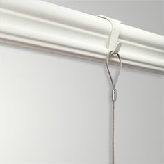 a white curtain is hanging on the side of a window with a chain attached to it