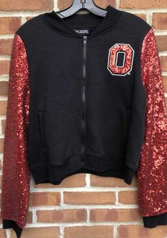 Keep the chill out with this Ohio State Buckeyes Womens Black Sequins Sleeve Bomber Light Weight Jacket! Cheer on the Buckeyes in this The Ohio State University Light Weight Jacket. With a sequins team logo on left chest, you won't want to be caught without this Light Weight Jacket on gameday. Bomber silhouette, All sequins sleeve, Center front zipper, Hand pockets, Ribbed collar, sleeve cuffs, and waistband, 4 Fall Fitted Outerwear With Contrast Sequin, Fitted Contrast Sequin Outerwear For Fall, Black Outerwear With Contrast Sequin For Winter, Winter Black Outerwear With Contrast Sequin, Casual Fall Outerwear With Sequins, Casual Sequined Outerwear For Fall, Casual Winter Outerwear With Sequins, Casual Sequined Outerwear For Winter, The Ohio State University