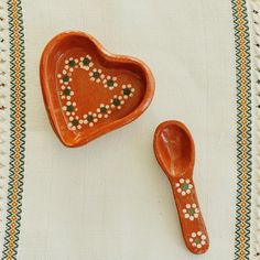 two ceramic heart shaped dishes sitting on top of a tablecloth covered place mat with beaded trimmings