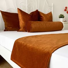 a white bed topped with lots of brown pillows