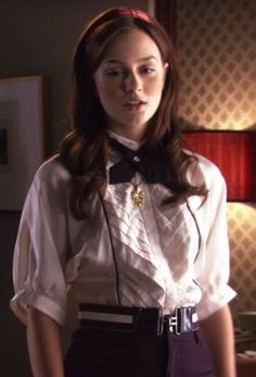 a woman wearing a white shirt and black bow tie standing in front of a lamp