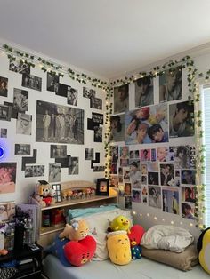 a bedroom with many pictures on the wall and stuffed animals in front of the bed