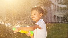 a young boy is playing in the sprinkles from a water hose on his back yard