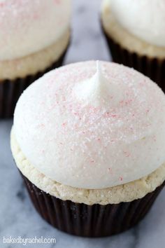 three cupcakes with white frosting and pink sprinkles on top