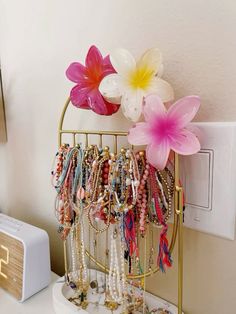 a bunch of bracelets and flowers on a gold stand next to an alarm clock