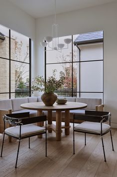 a dining room table with four chairs and a bench in front of large windows that look out onto the outdoors