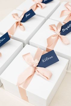 four white boxes with pink bows and name tags on them