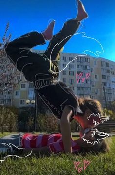 a man doing a handstand on the ground in front of a tall building