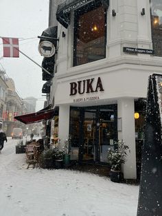 a building that is covered in snow on the side of a street with people walking by it